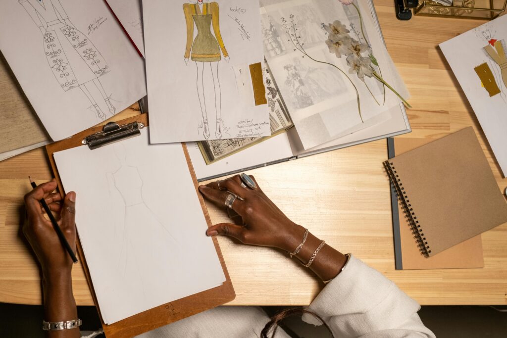 Fashion designer creating sketches and designs in an artistic workspace, from above view.
